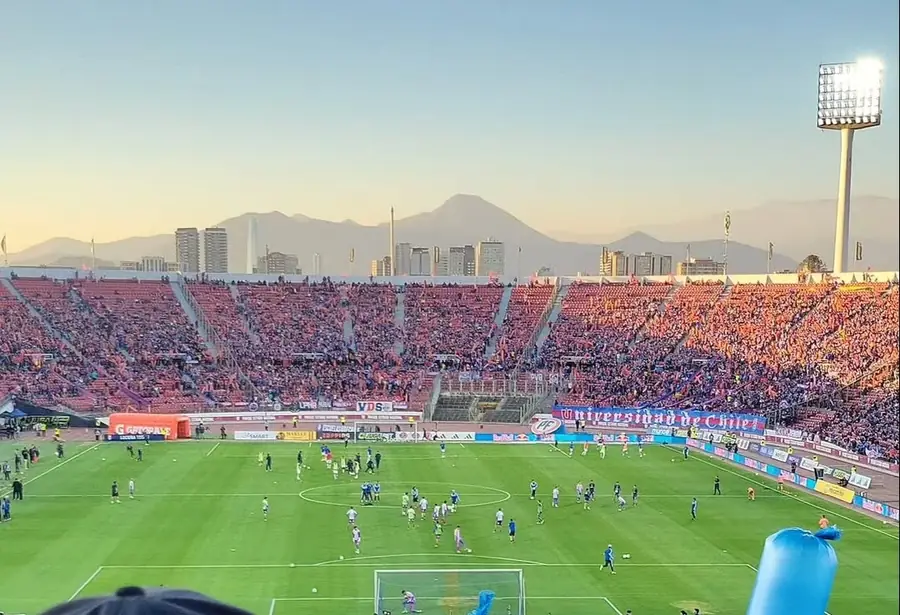 Estadio lleno al atardecer con la cordillera de fondo